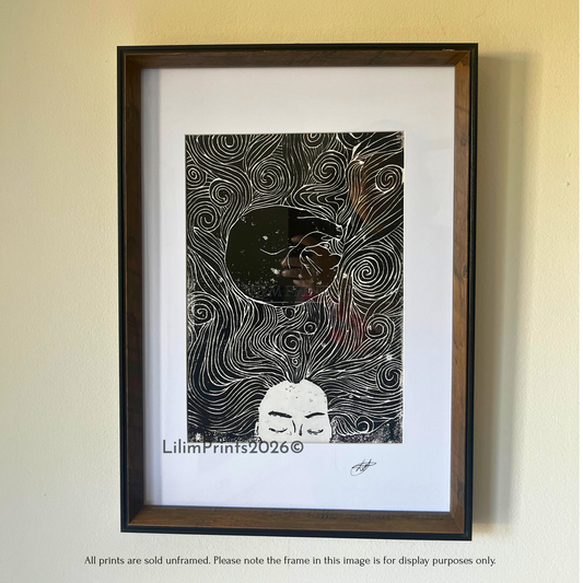 A lino print image in a frame hung on the wall. a sleeping woman and a cat curled in her swirling hair. 